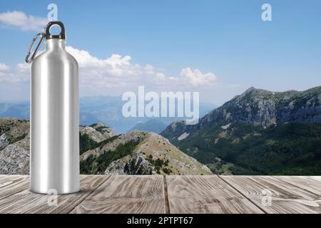 Bouteille d'eau en aluminium sur une table en bois et belle vue sur les montagnes, espace pour le texte Banque D'Images