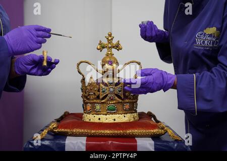 Dawn Jenks et Donna Oluban, chocolatiers du monde de Cadbury, ajoutent les touches finales à une réplique de 45cm grands chocolats de la couronne de St Edward à Cadbury World à Birmingham. Il a fallu deux jours pour construire leur version de la couronne qui sera utilisée au couronnement du roi Charles III en utilisant du chocolat blanc et du lait, et dépoussiéré avec des paillettes comestibles. Date de la photo: Mercredi 26 avril 2023. Banque D'Images