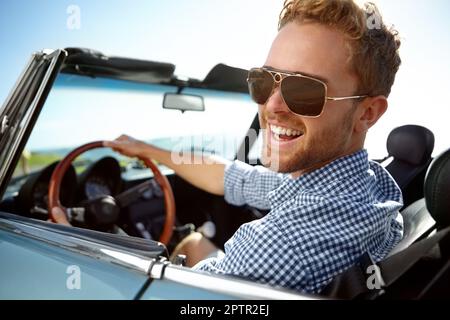 C'est facile à regarder cool dans cette voiture. Un beau jeune homme qui conduit dans son cabriolet un après-midi ensoleillé Banque D'Images