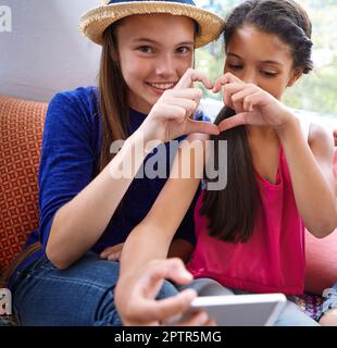 J'aime ma bestie. deux amis adolescents prenant un selfie tout en faisant une forme de coeur avec leurs mains. Banque D'Images