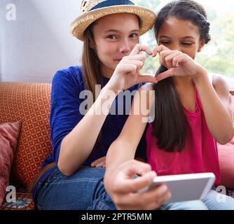 J'adore ma bestie. deux amis adolescents prenant un selfie tout en faisant une forme de coeur avec leurs mains. Banque D'Images