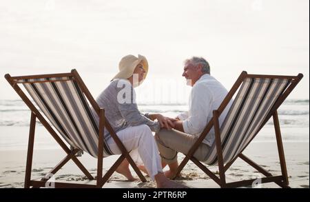 Notre amour a bien vieilli, pas de miel. Photo en longueur d'un couple senior affectueux qui a une discussion intime sur des chaises longues au Banque D'Images