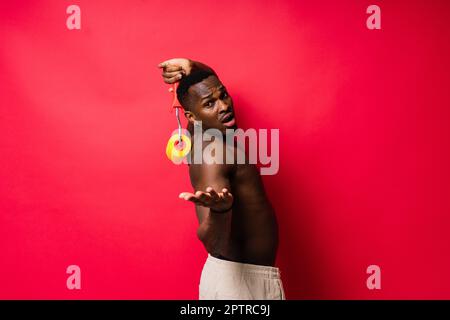 Un peintre africain s'est concentré sur le travail tenant un rouleau professionnel pour peindre un mur intérieur, studio. Banque D'Images