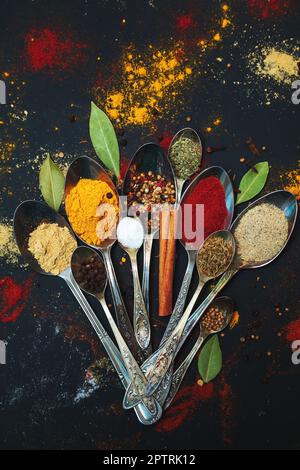 Épices et assaisonnements pour la cuisson en cuillères sur fond sombre. Banque D'Images