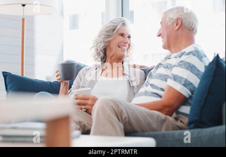 La maison est toujours heureuse de vous. un couple senior appréciant une pause-café relaxante sur le canapé à la maison. Banque D'Images