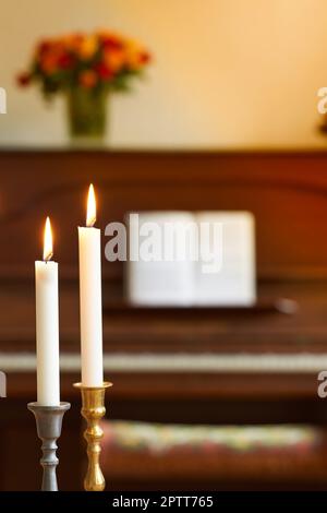 Deux bougies fines dans les supports de bâton de bougie brûlant contre le piano flou et le fond de bouquet de fleurs. Photophores élégantes en or et argent Banque D'Images