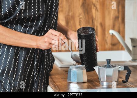 Vue rapprochée de la main d'une femme qui verse du café moulu la cafetière geyser Banque D'Images