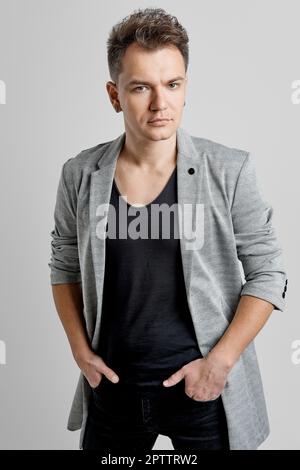 Portrait d'un beau homme portant une veste en laine, une chemise noire et un Jean. Banque D'Images