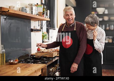 Peut-être un peu de poivre pour un coup de pied. un heureux couple d'âge mûr s'amusant tout en préparant un repas ensemble à la maison Banque D'Images