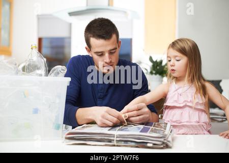 Daddys petit assistant. Une jeune famille respectueuse de l'environnement travaille ensemble pour recycler Banque D'Images