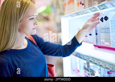 Shes un acheteur avisé. une jeune femme parcourant les étagères d'une pharmacie Banque D'Images