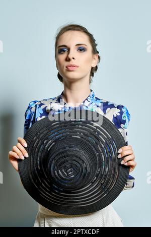 Gros plan portrait d'une belle fille avec chapeau noir à large bord dans les mains. Banque D'Images