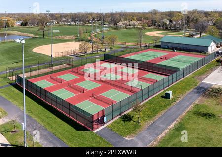 Vue aérienne d'un terrain de pickleball avec terrains rouges et verts dans un parc de banlieue avec terrains de baseball et de softball au début du printemps. Banque D'Images