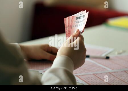 Remplir un billet de loterie. Une jeune femme détient le billet de loterie avec une rangée complète de numéros sur le fond des feuilles vierges de la loterie. Jeu con Banque D'Images