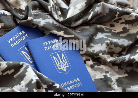 Passeport ukrainien étranger sur tissu avec texture de camouflage militaire pixellisé. Tissu avec motif camouflage en forme de pixel gris, marron et vert et Royaume-Uni Banque D'Images