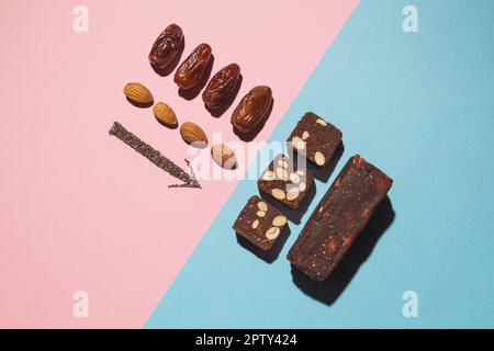 Barres de bonbons aux fruits à la date des protéines fitness avec fruits à coque et amande et graines de chia et de pavot, vue du dessus sur fond rose bleu avec espace et lieu de copie Banque D'Images