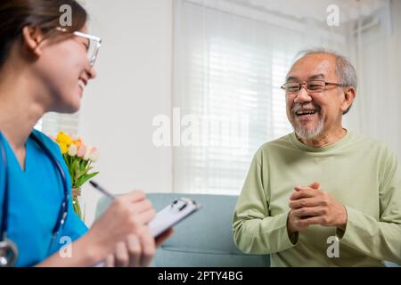 Un homme âgé prend un médecin à la maison pour parler de problèmes de santé, une jeune infirmière asiatique écrivant un presse-papiers de prescription tout en parlant pendant la visite à la maison sic Banque D'Images