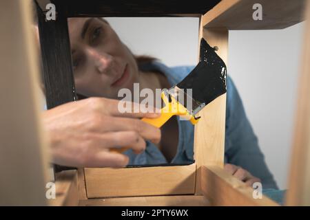 Les jeunes femmes se préparant à restaurer un escabeau pour les enfants comme une amélioration de maison de passe-temps. Sur une table couverte. Peindre avec un pinceau Banque D'Images