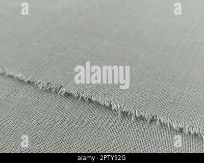 Bord déchiré de tissu laineux fin en vert ou bleu. Fils lâches sur le bord d'un morceau de textile. Gros plan. Arrière-plan tissé. Col vert pastel calme Banque D'Images