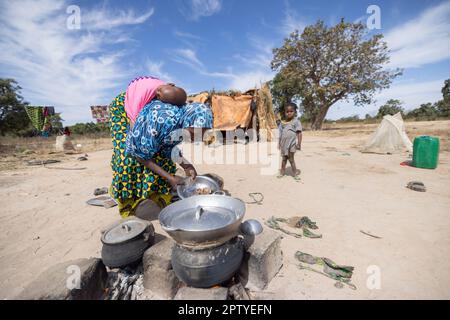 Mère cuisinant un repas sur un feu ouvert devant la maison de la famille dans la région de Ségou, Mali, Afrique de l'Ouest. 2022 Mali sécheresse et crise de la faim. Banque D'Images