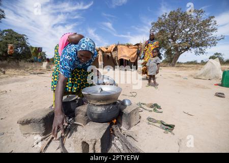 Mère cuisinant un repas sur un feu ouvert devant la maison de la famille dans la région de Ségou, Mali, Afrique de l'Ouest. 2022 Mali sécheresse et crise de la faim. Banque D'Images