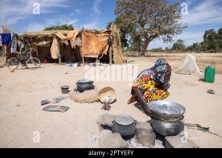 Mère cuisinant un repas sur un feu ouvert devant la maison de la famille dans la région de Ségou, Mali, Afrique de l'Ouest. 2022 Mali sécheresse et crise de la faim. Banque D'Images