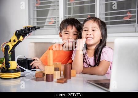 Deux enfants programmant et testant robot ARM leur science, Kid petite fille programme code au robot avec ordinateur portable et le garçon test avec la télécommande Banque D'Images