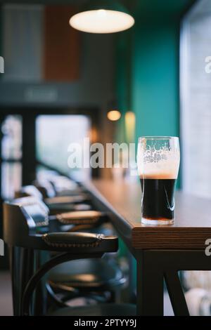 Photo verticale, gros plan sur un verre de bière sur le comptoir du bar, mise au point sélective. Bar View, flou de mise au point, idée de décoration de bar ou photo pour l'intérieur Banque D'Images