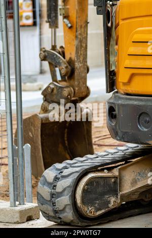 Détail du train de roulement d'une pelle hydraulique caterpillar qui et de la pelle pour extraire la terre du sol d'un trottoir urbain Banque D'Images