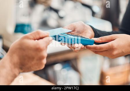 Gros plan d'un employé acceptant un paiement par carte de crédit sans contact à l'aide de la technologie nfc d'un client dans un café ou un magasin. Mains de l'homme tapotant la mach de carte Banque D'Images