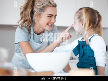 Maman gaie jouant et faisant cuire avec sa fille. Bonne femme mettant de la farine sur ses filles nez.Femme caucasienne ayant plaisir à cuire avec son daugh Banque D'Images