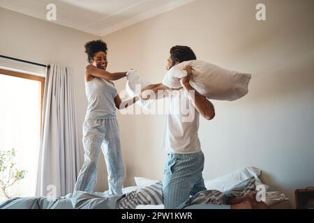 Taie d'oreiller, jouer et se lier avec un couple heureux jouer, se lier et passer du temps ensemble dans leur chambre à la maison. Rire, s'amuser et f Banque D'Images