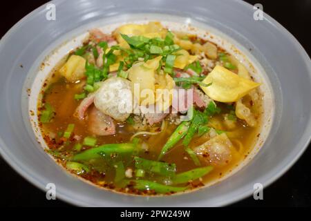 Nouilles jaunes aux œufs dans une soupe épicée de porc, photo de stock Banque D'Images