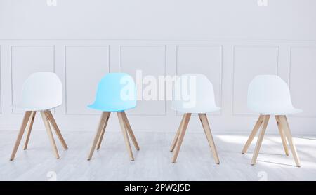 Quatre chaises alignées dans une salle d'attente de bureau. Un président bleu et trois blancs, attendant que des candidats potentiels soient assis, interviewés et marmite Banque D'Images