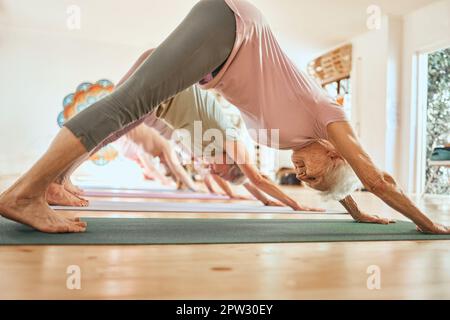 Yoga, exercice et femme âgée en studio, classe et leçon pour le bien-être, les soins du corps et la forme physique. Sports, équilibre et les femmes âgées faisant le chien vers le bas Banque D'Images