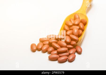 Fumarate ferreux ou vitamines sur une cuillère en bois sur fond blanc Banque D'Images