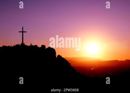 Traversez au sommet d'une montagne avec des silhouettes de personnes et un coucher de soleil violet, orange et jaune Banque D'Images