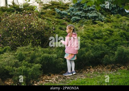 Chasse au Trésor pour les enfants dans le parc. Fille apprenant sur l'environnement. Activité d'éducation naturelle pour la Journée mondiale de la Terre. Explorer au printemps. Banque D'Images