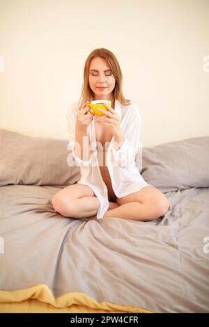 Femme adulte en robe fermant les yeux tout en ayant une tasse de café noir fraîchement préparé Banque D'Images