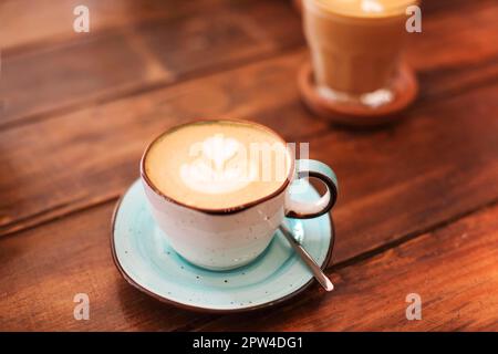 Du dessus des tasses en céramique sur les soucoupes fraîchement brassées latte avec les cœurs sur la mousse Banque D'Images
