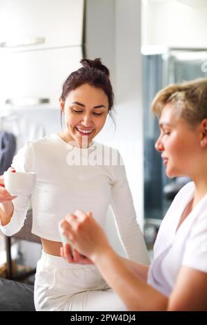 Cosmétique féminine appliquant de la crème hydratante sur les mains du client pendant soin de la peau en salon Banque D'Images