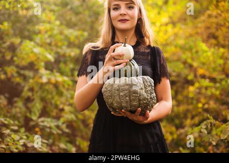 Portrait d'une belle jeune femme blonde avec de longs cheveux droits et un maquillage de vamp foncé regardant l'appareil photo, portant la robe noire guipure, tenue Banque D'Images