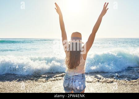 Elle aime la liberté qu'elle obtient de la plage. Vue arrière d'une femme méconnue passant la journée à la plage. Banque D'Images