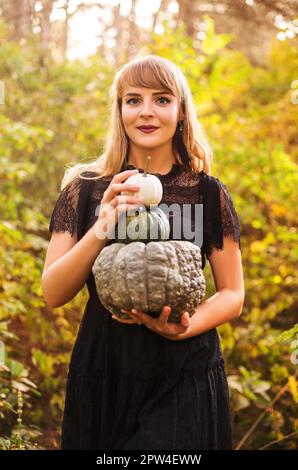 Portrait d'une belle jeune femme blonde avec de longs cheveux droits et un maquillage de vamp foncé regardant l'appareil photo, portant la robe noire guipure, tenue Banque D'Images