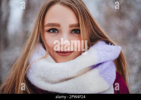 Gros plan photo de la belle femme avec un look net, la moitié de la jeune femme visage recouvert d'un foulard tricoté de couleur claire, fille regardant dans l'appareil photo avec Banque D'Images