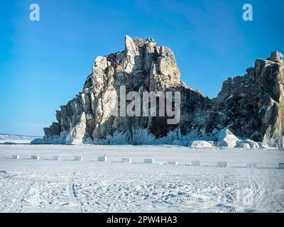 Journée d'hiver ensoleillée au lac Baikal. Paysage de montagne au coucher du soleil avec glace de rupture naturelle dans l'eau gelée sur le lac Baikal, Sibérie, Russie Banque D'Images