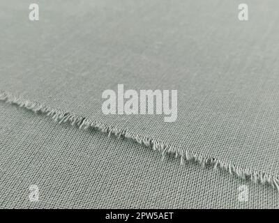 Bord déchiré de tissu laineux fin en vert ou bleu. Fils lâches sur le bord d'un morceau de textile. Gros plan. Arrière-plan tissé. Col vert pastel calme Banque D'Images