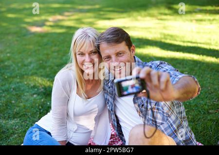 Allons en prendre un pour les enfants. un couple séduisant prenant un selfie dans le parc Banque D'Images