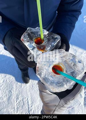 Baïkal Ice Bar : homme et femme buvant de l'alcool fort à partir de glaçons avec trou. Attraction touristique populaire pendant l'hiver alias Baikal Kiss Banque D'Images