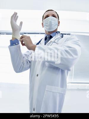 L'enfer prendre soin de vos besoins médicaux. un médecin qui met un gant en caoutchouc Banque D'Images